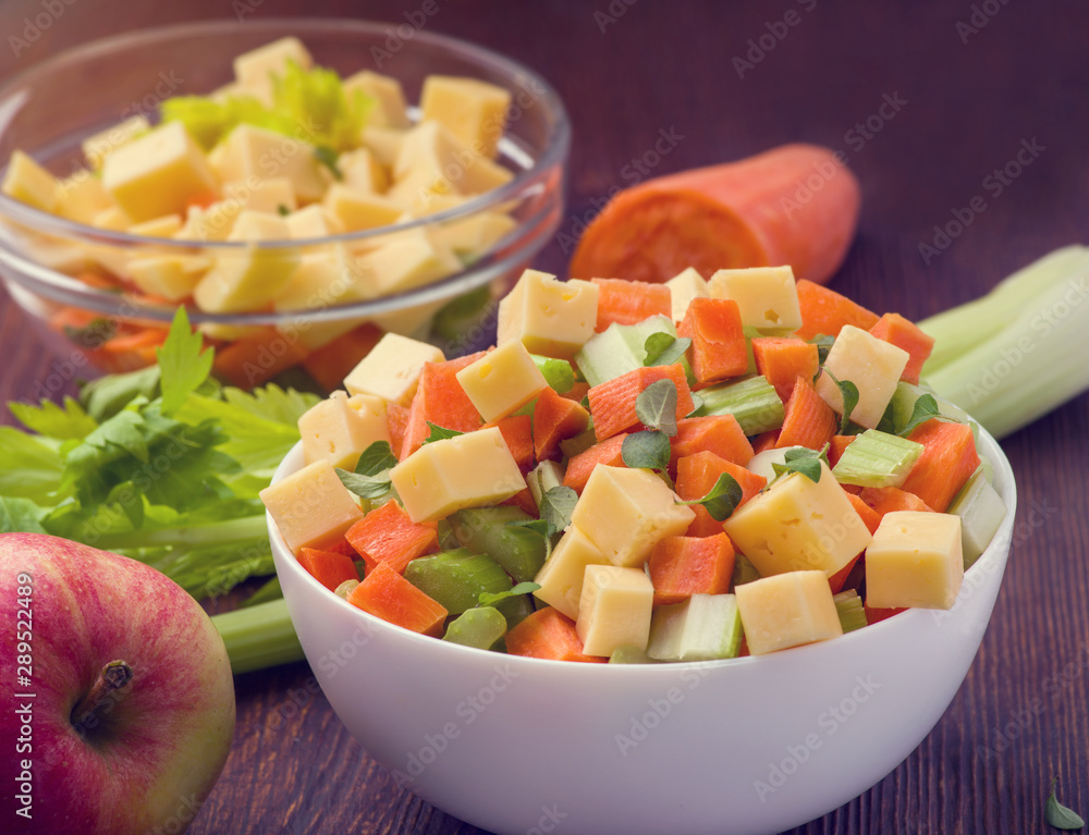 Vitamin salad of celery stalks, carrots, apples and cheese. Vegetable salad with cheese cut into cubes in a plate and a number of ingredients are. Vitamin salad of celery stalks, carrots, apples and cheese. Vegetable salad with cheese cut into cubes in a plate and a number of ingredients are.
