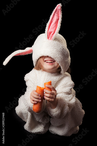 Studio shot of a 5 years girl with a bunny costume against a black background photo