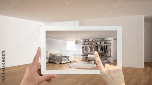 Augmented reality concept. Hand holding tablet with AR application used to simulate furniture and design products in empty interior with parquet, luxury bedroom with walk-in closet photo