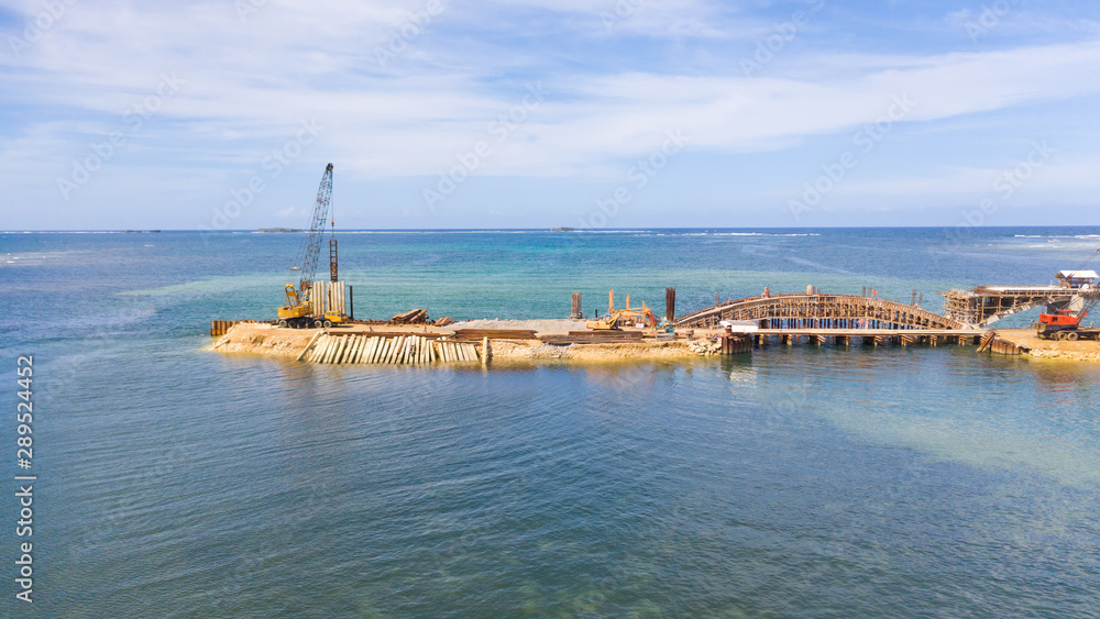 Construction of a bridge across the bay. Construction equipment on the bridge, top view. New bridge on the island of Siargao, Philippines.