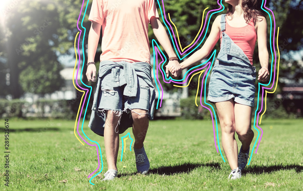 Obraz premium holidays, vacation, love and people concept - happy teenage couple walking in summer park with glowing lines
