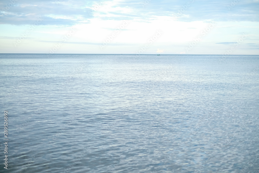 Beautiful white clouds on blue sky over calm sea with sunlight reflection,  Tranquil sea harmony of calm water surface. Sunny sky and calm blue ocean.