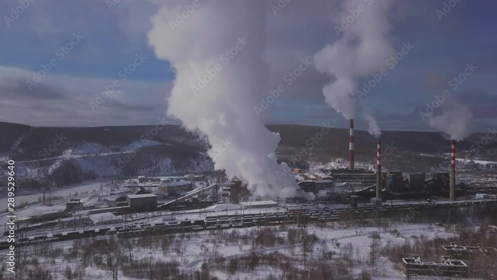 A factory emitting steam and smoke into the atmosphere causing pollution. Drone view. A factory emitting steam and smoke into the atmosphere causing pollution. Drone view.