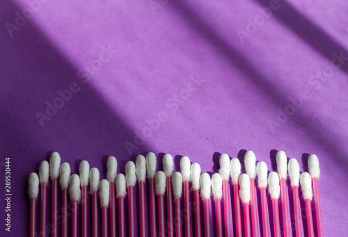 Single use plastic and color concept. Pink plastic cotton swabs on purple background