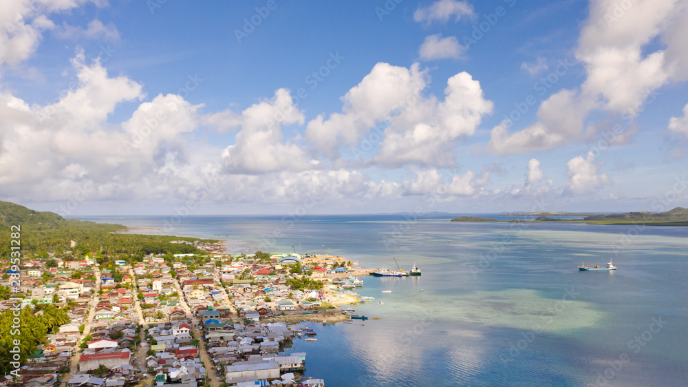 Sea port in the city of Dapa, Philippines. Fishing village and ships, view from above. Seascape in sunny weather.