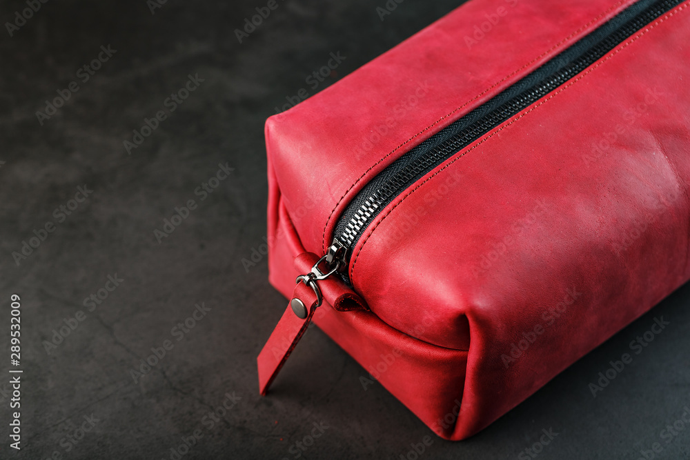 Naklejka premium Bag for cosmetics and jewelry made of genuine red leather, on a dark background. Handwork.