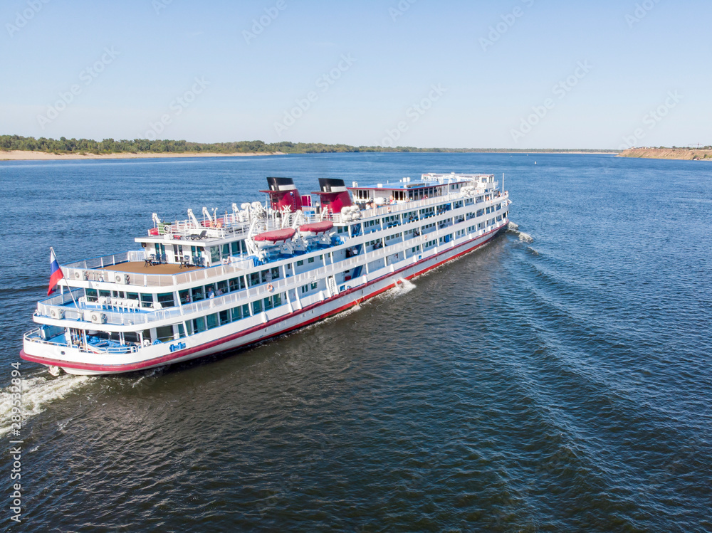 A large cruise ship with tourists on board runs along the Volga downstream towards Astrakhan. Volgograd. Russia A large cruise ship with tourists on board runs along the Volga downstream towards Astrakhan. Volgograd. Russia