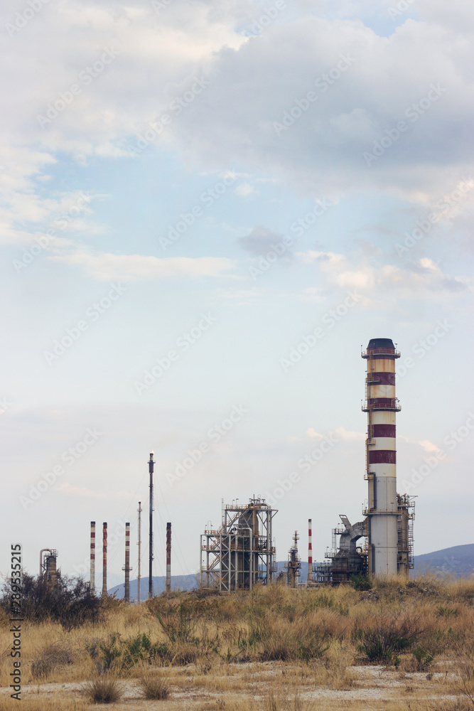 Oil refinery with visible smoke coming out of chimneys; pollution concept, with copy space