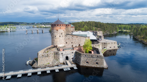 Beautiful aerial view of Olavinlinna, Olofsborg ancient fortress. Tower castle located in Savonlinna city on a cloudy summer day with dramatic sky. Finland. Drone photography from above. photo