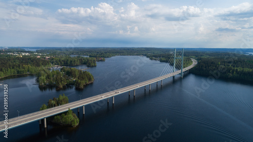  Aerial view of blue lakes  green forests and bridge.  Sunny summer day in rural Finland. Drone photography from the air.