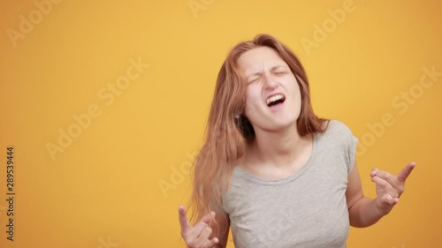 brunette girl in gray t-shirt over isolated orange background shows emotions