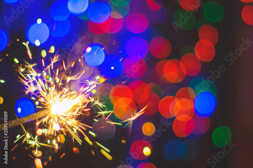 New year holiday Sparkler on the background of bright colorful bokeh. Blur.