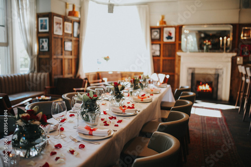 Wedding table setting decorated with fresh flowers and silverware. Concept of fine dining, catering and exclusive private hire of an event space. Banquet table set up for a wedding reception or dinner