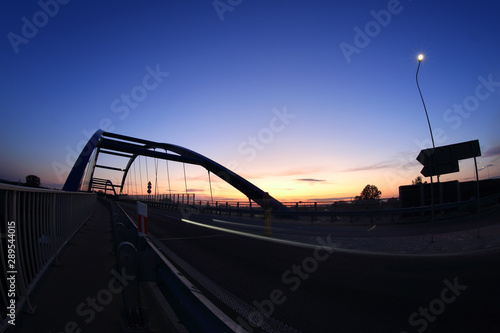 Most wiszący nad autostradą po zachodzie słońca, samochody.