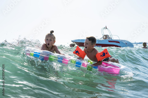 Happy family lifestyle. Сhildren jumping and splashing with fun in breaking waves. Brother and sister. © Evgenia