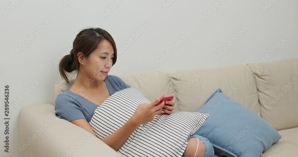 Woman watch on mobile phone and sit on sofa at home Woman watch on mobile phone and sit on sofa at home