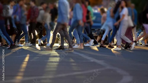 People crowd crossing street in front of stopped cars. Slow motion shot photo