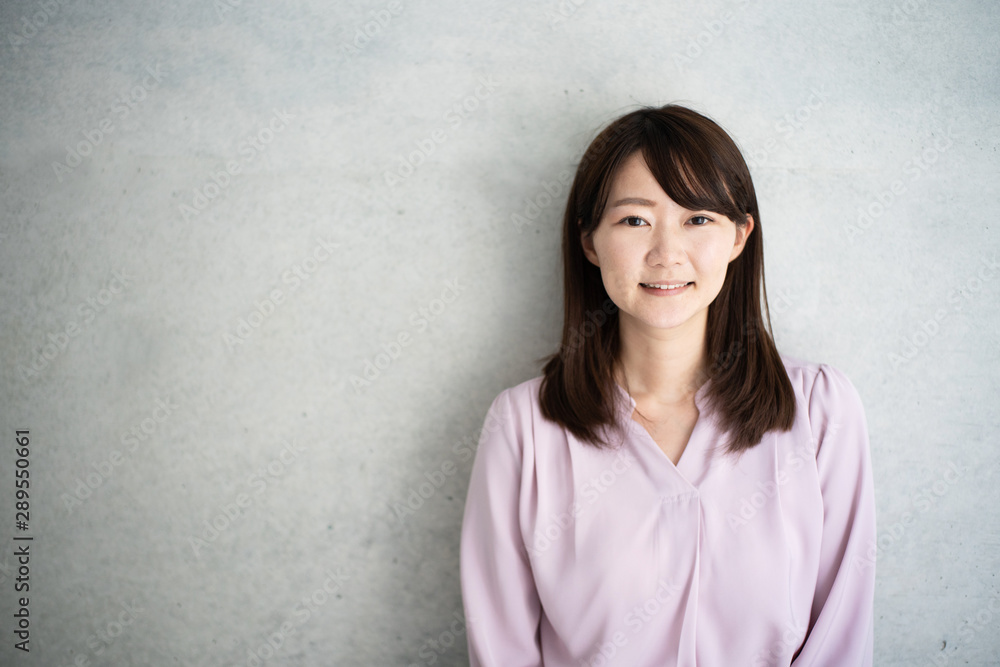Young business woman standing against concrete wall Young business woman standing against concrete wall