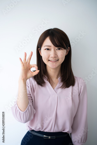 Young business woman showing OK sign againt white background