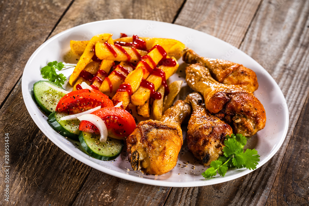 Grilled chicken drumsticks with french fries and vegetables Grilled chicken drumsticks with french fries and vegetables