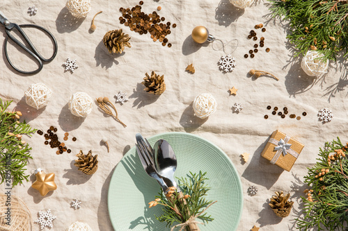 Christmas decoration. Festive plate and cutlery, laptop with Christmas decorations at sunny day. Holiday, New Year background, Hard light with shadows