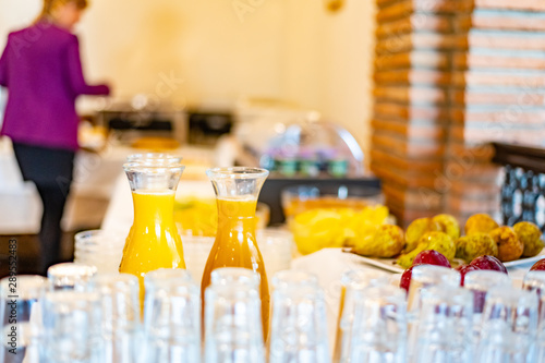 Orange juice glass bottles and some glasses with a breakfast buffet background, with narrow depth of field