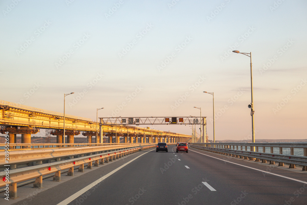 motorway over the bridge with transport, on the right, the Crimean bridge under construction at dawn