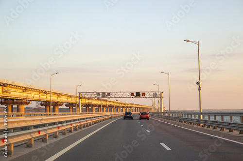 motorway over the bridge with transport, on the right, the Crimean bridge under construction at dawn