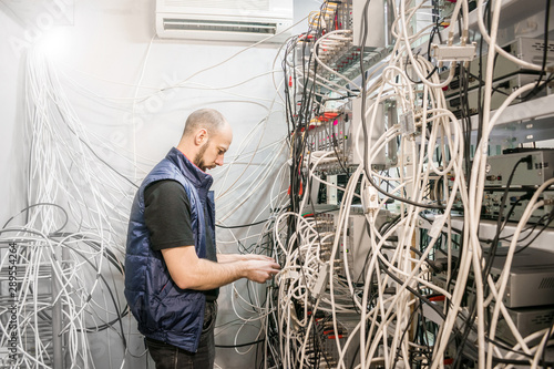 Fotografie Specialist connects coaxial television wires in the rack of the TV station server room