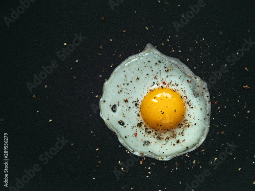 Fried egg. Close up view of the fried egg on a frying pan. Salted and spiced fried egg on cast iron pan.