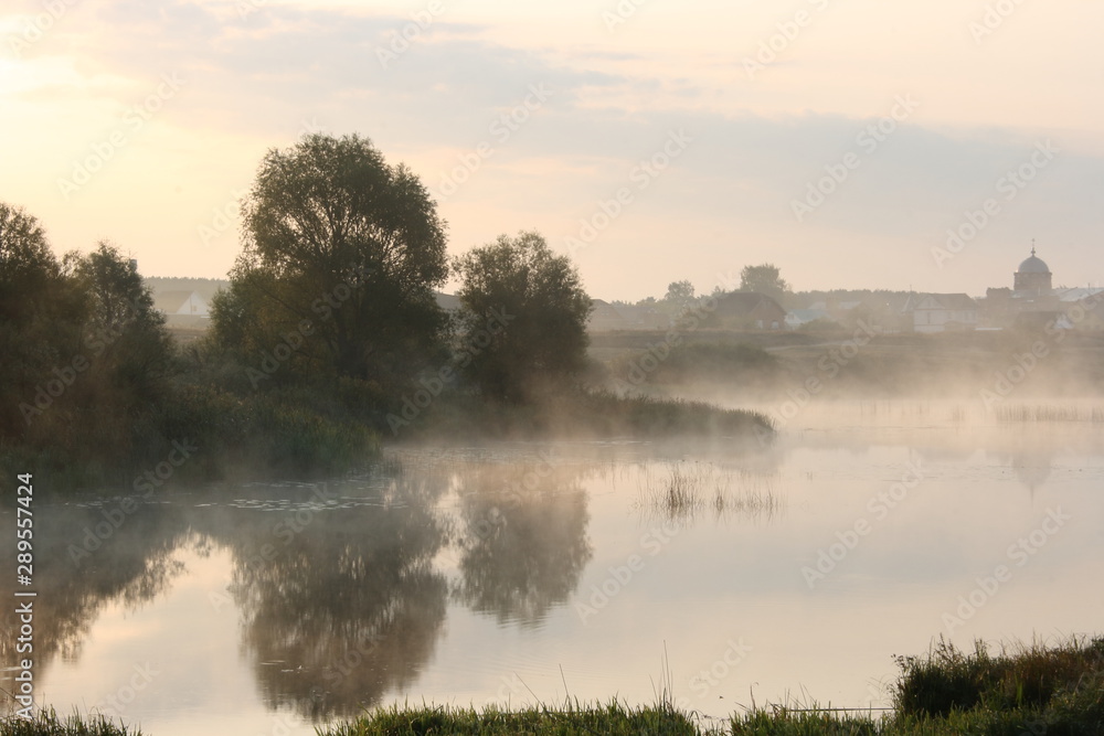 Fototapeta premium Morning fog on the river overlooking the village