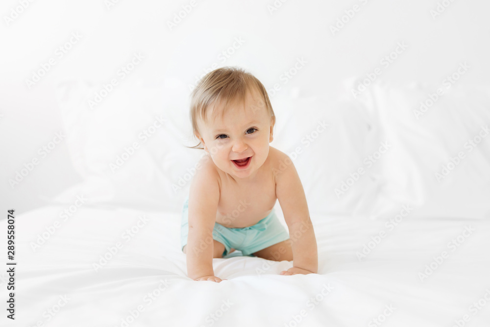 Happy shirtless baby crawling on white bed Happy shirtless baby crawling on white bed