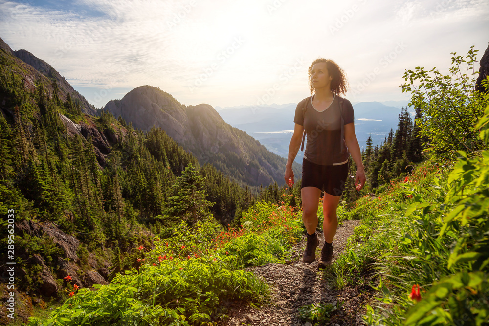 Fototapeta premium Adventurous girl hiking the beautiful trail in the Canadian Mountain Landscape during a vibrant summer evening. Taken at Mt Arrowsmith, near Nanaimo, Vancouver Island, BC, Canada.