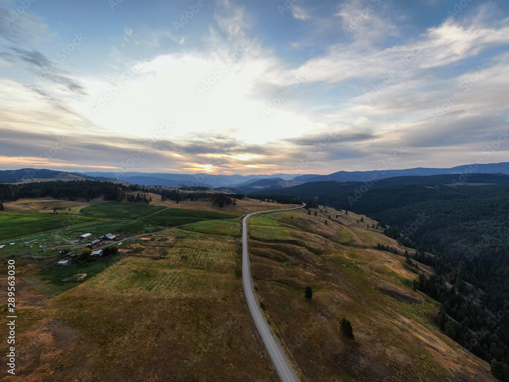 Aerial Panoramic View of a Scenic Highway in the Country Side during a colorful summer sunrise. Taken in the Kootenay, near Rock Creek, British Columbia, Canada.