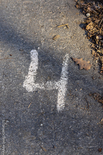 Arabic figure 4 (four) painted with white on an asphalt road. Photo with selective focus