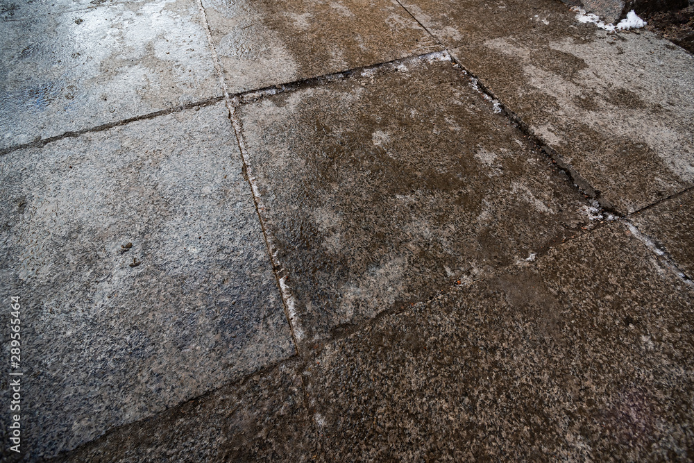 Obraz premium Wet surface of paving stones with pieces of ice