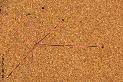 Detective concept with red thread connects pins on cork board