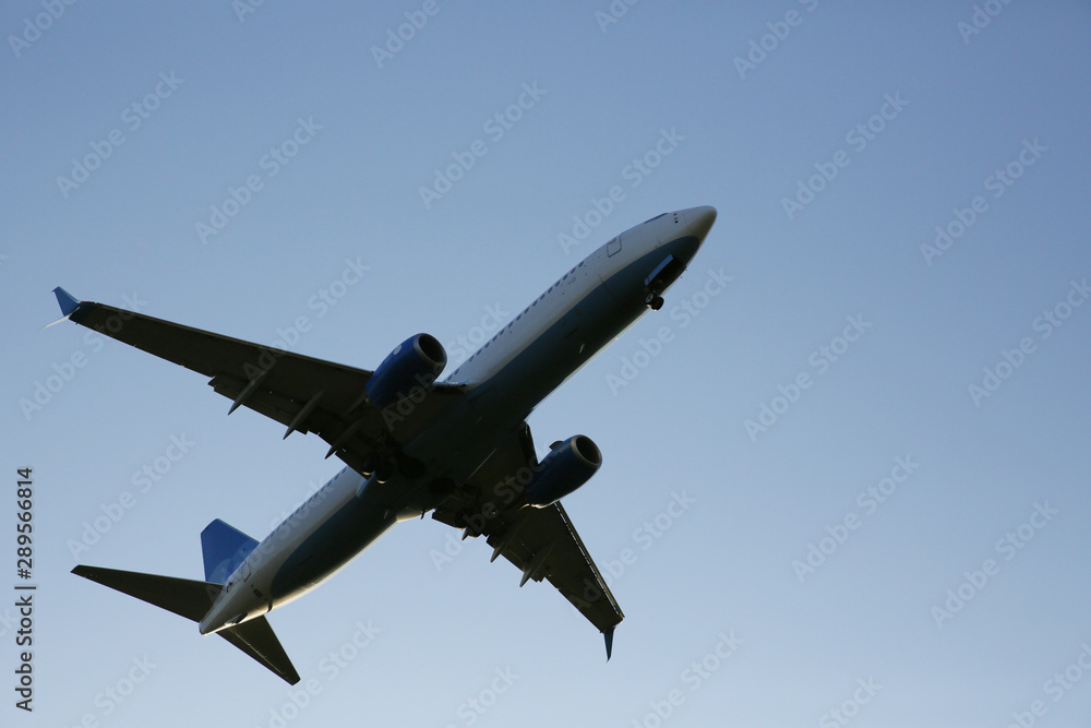 Obraz premium Closeup Beautiful Airplane in a blue clear sky. The plane takes off or lands for landing. Air passenger transport.