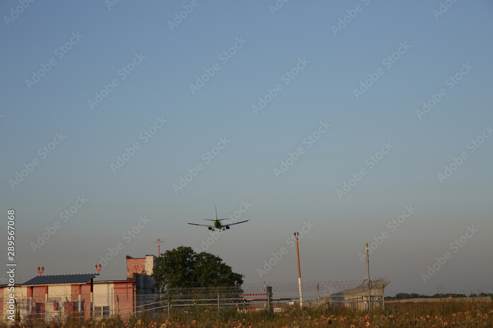Obraz premium The plane lands at the airport at sunset. Landing strip and security zone of the airport. Air passenger transport.