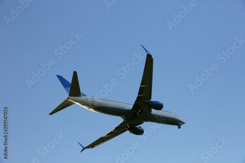 Closeup Beautiful Airplane in a blue clear sky. The plane takes off or lands for landing. Air passenger transport.