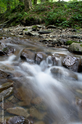 Small waterfall in the mountain forest with stones  long exposure