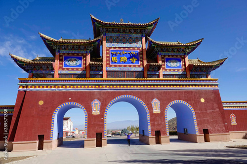 Cheerful woman travelling around China poses under the majestic temple entrance.