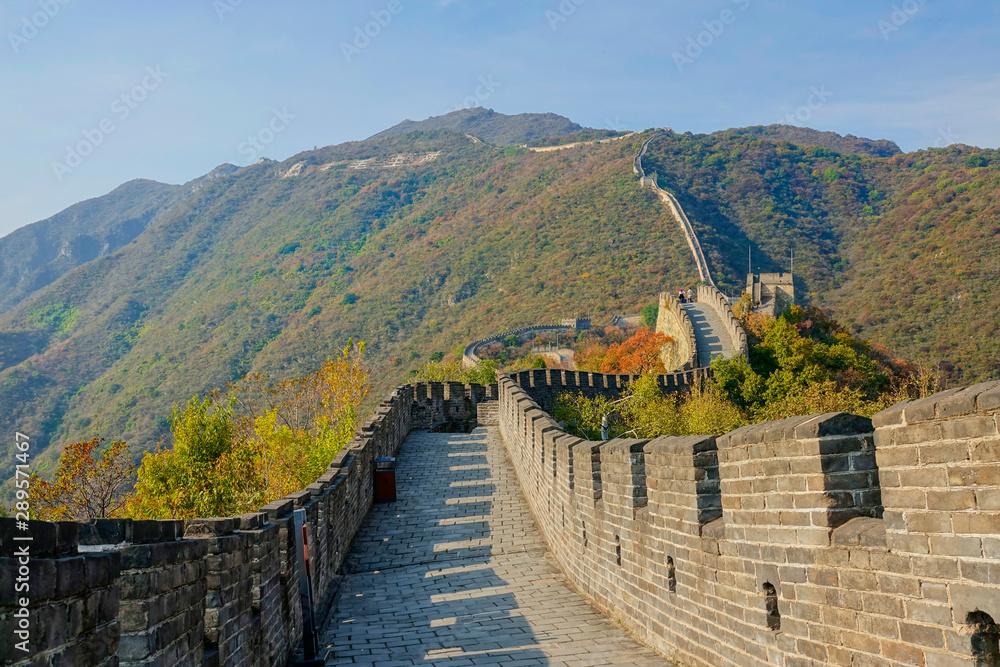 Travelers walk down walkway on top of famous Great Wall of China on sunny day Travelers walk down walkway on top of famous Great Wall of China on sunny day