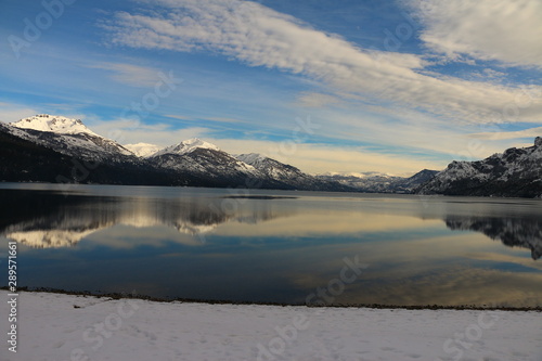 vista de gran angular de un lago con montañas, nieve y nubes