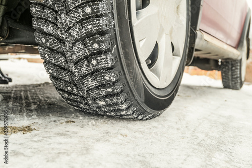 Fotografi Car wheel on a slippery snowy winter road. Winter studded tires.
