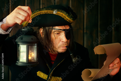 Portrait of a medieval pirate reading a scroll with a lantern in his hand