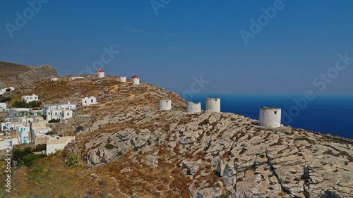 Aerial drone photo of picturesque windmills in main town or chora of Amorgos island built on top of cliff overlooking the Aegean blue sea, Cyclades, Greece
