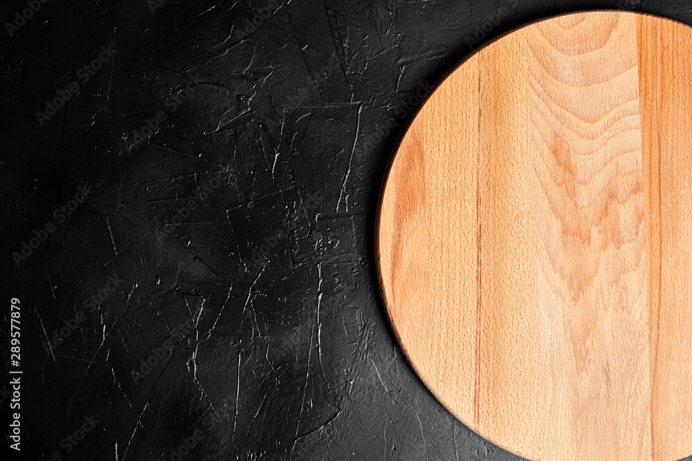 Cutting board on black stone table. Empty round beech wooden chopping board  on dark background, top view Stock Photo | Adobe Stock