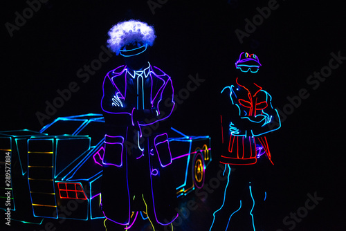 dancer in led suit near neon car .