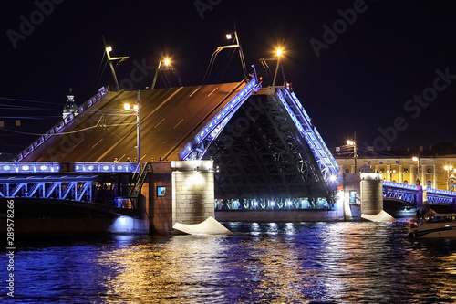 Drawbridge across the Neva River at night. Illuminated Palace Bridge raising. Ripples, colorful reflection of night lights (Saint Petersburg, Russia) photo